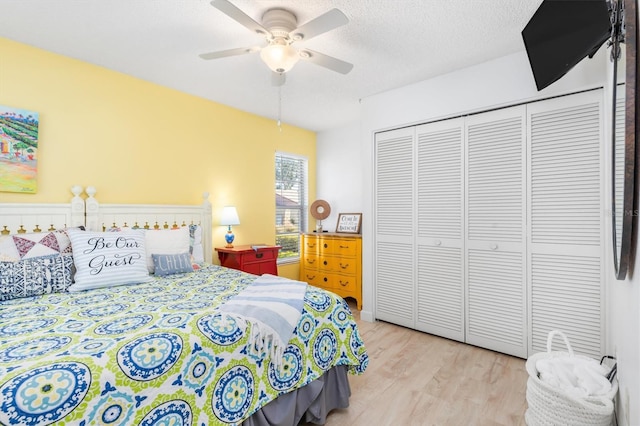 bedroom featuring ceiling fan, a closet, a textured ceiling, and light wood-type flooring