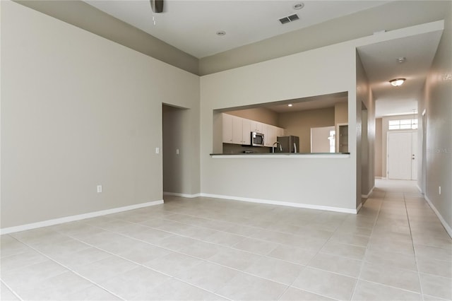 unfurnished living room with light tile patterned floors and a towering ceiling