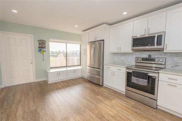 kitchen featuring white cabinetry, appliances with stainless steel finishes, decorative backsplash, and light hardwood / wood-style flooring