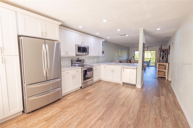 kitchen with sink, white cabinetry, light wood-type flooring, appliances with stainless steel finishes, and backsplash