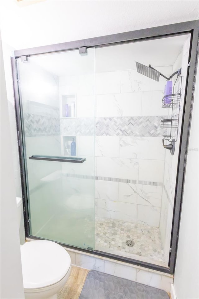 bathroom with a shower with door, tile patterned floors, and toilet