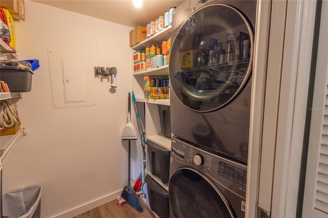 laundry area with stacked washer and clothes dryer, electric panel, and wood-type flooring