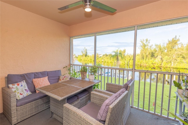 sunroom featuring a water view and ceiling fan