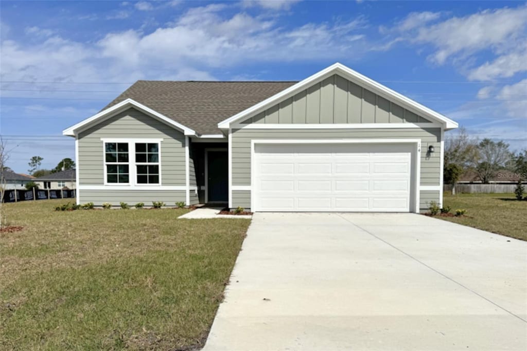 ranch-style house with a garage, concrete driveway, a shingled roof, and a front lawn