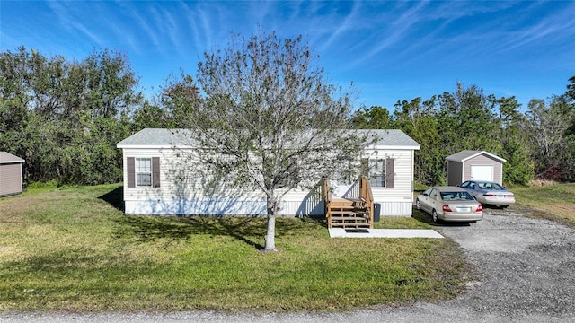 view of front of home with a garage, an outdoor structure, and a front lawn