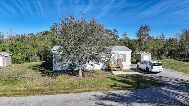 view of front of property featuring a front lawn and a storage shed