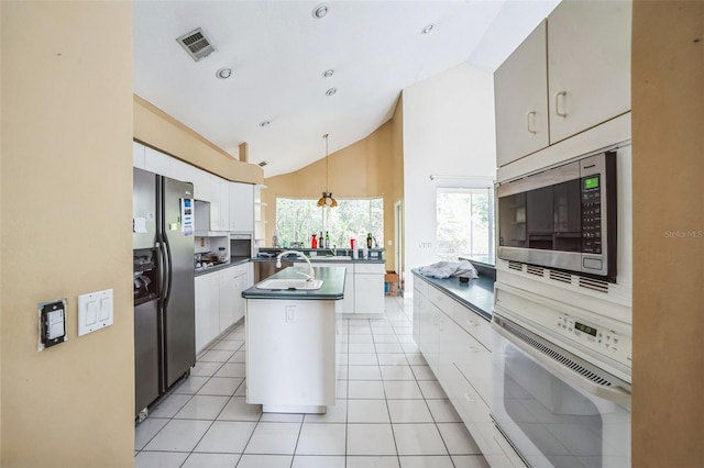 kitchen with white cabinetry, appliances with stainless steel finishes, a kitchen island with sink, and light tile patterned floors