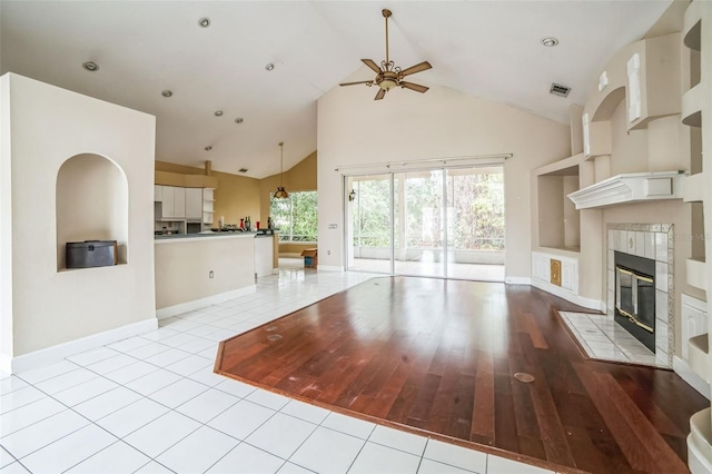 unfurnished living room with ceiling fan, light tile patterned floors, built in features, and a fireplace