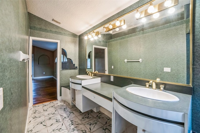 bathroom featuring vaulted ceiling, vanity, and a textured ceiling