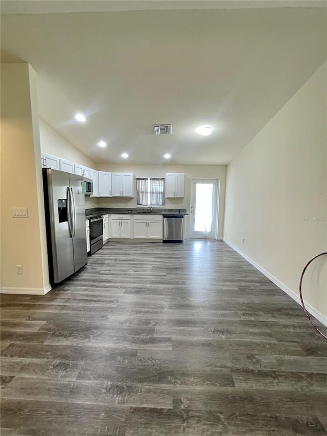 kitchen featuring white cabinetry, dark wood-type flooring, stainless steel appliances, and vaulted ceiling