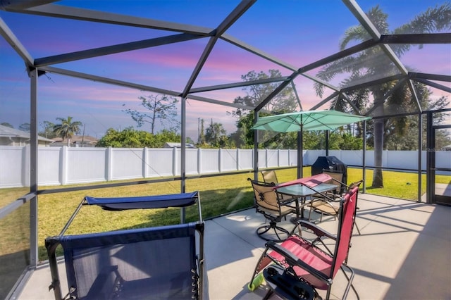 patio terrace at dusk featuring a grill, a lanai, and a lawn