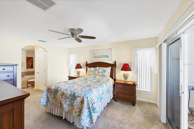 bedroom featuring multiple windows, light carpet, ceiling fan, and ensuite bath