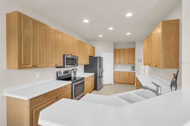 kitchen featuring light brown cabinetry, light tile patterned floors, stainless steel appliances, and kitchen peninsula