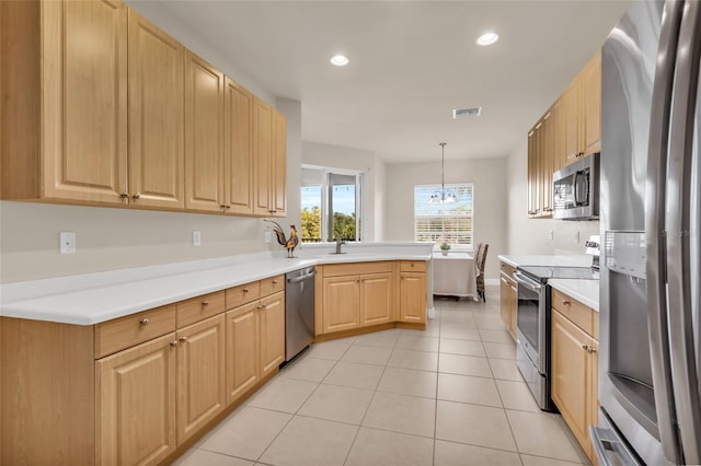 kitchen featuring light tile patterned flooring, appliances with stainless steel finishes, decorative light fixtures, kitchen peninsula, and light brown cabinets