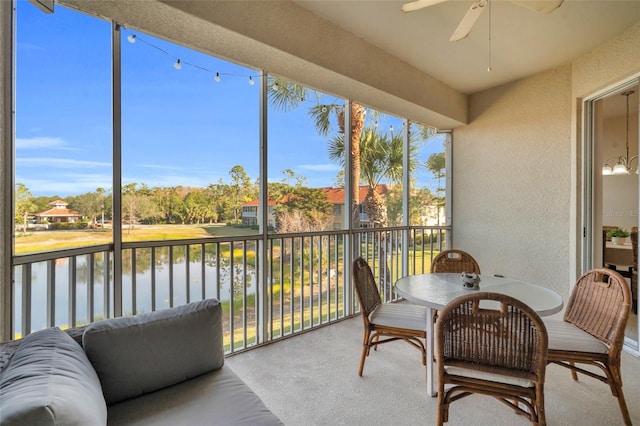 sunroom with ceiling fan and a water view