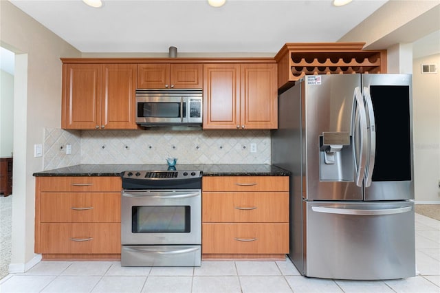 kitchen featuring tasteful backsplash, stainless steel appliances, light tile patterned flooring, and dark stone counters