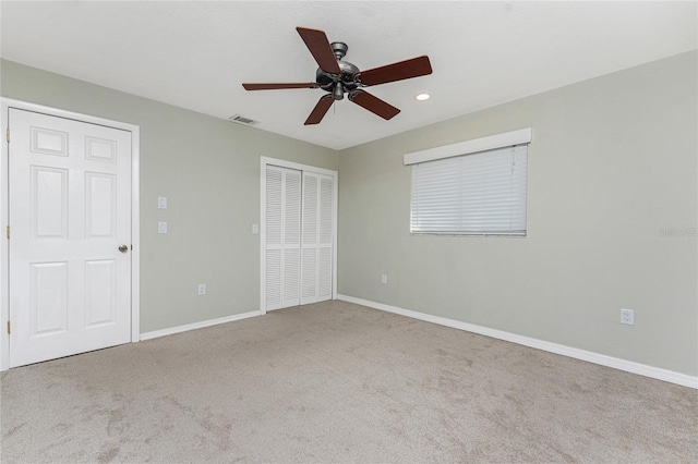 unfurnished bedroom featuring light carpet, a closet, and ceiling fan