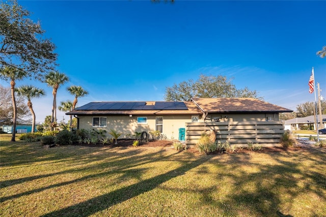 back of house featuring a yard and solar panels