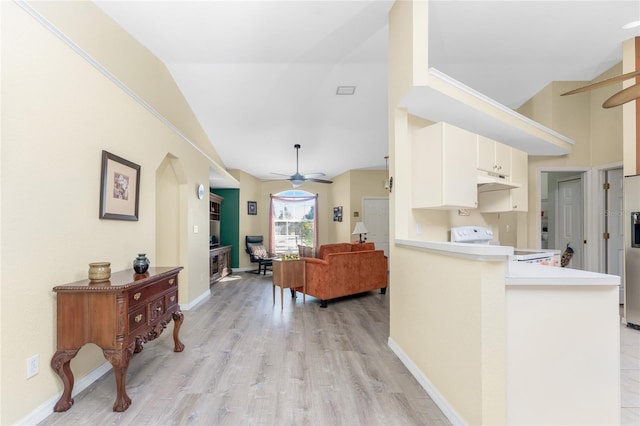 kitchen with ceiling fan, stove, vaulted ceiling, kitchen peninsula, and light wood-type flooring