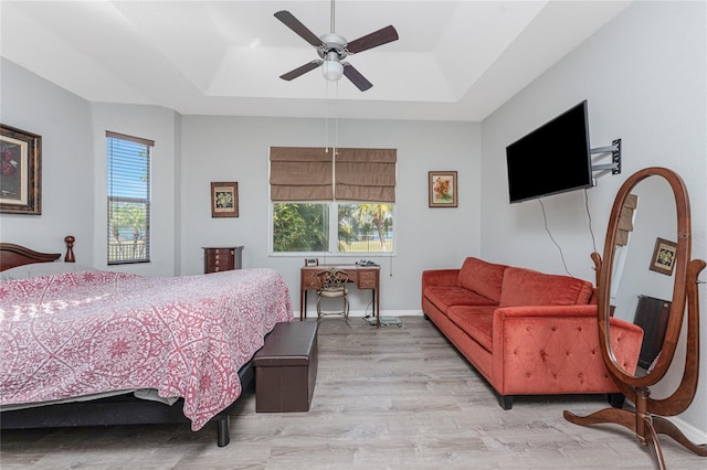 bedroom featuring ceiling fan, a raised ceiling, and light hardwood / wood-style floors