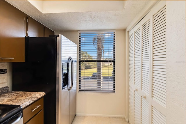 kitchen featuring tasteful backsplash, dark brown cabinets, stainless steel fridge, and a textured ceiling