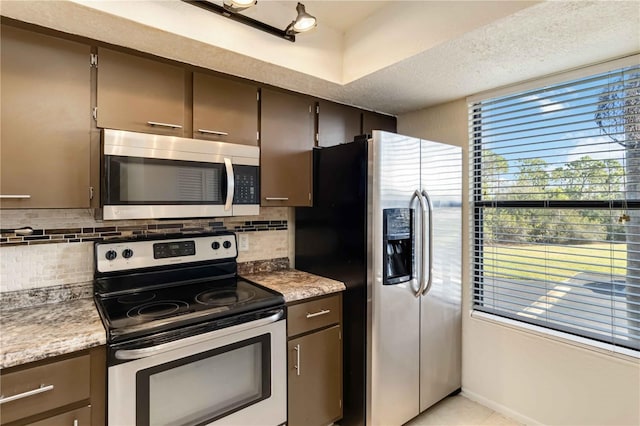 kitchen featuring dark brown cabinetry, decorative backsplash, and stainless steel appliances