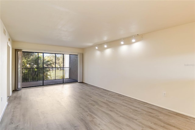 empty room with rail lighting and light wood-type flooring