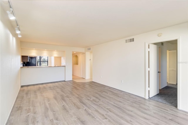 unfurnished living room featuring track lighting and light hardwood / wood-style flooring