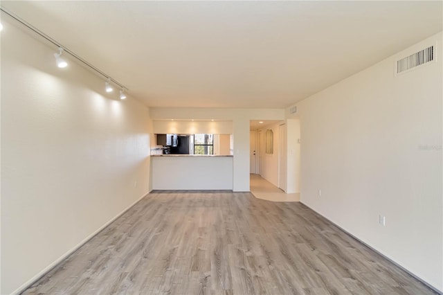 unfurnished living room featuring track lighting and light hardwood / wood-style floors