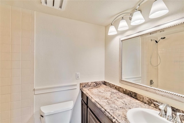 bathroom with a tile shower, vanity, a textured ceiling, and toilet