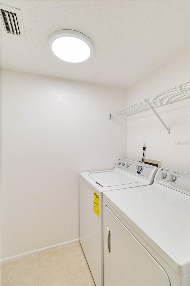 laundry area with light tile patterned floors and washer and dryer