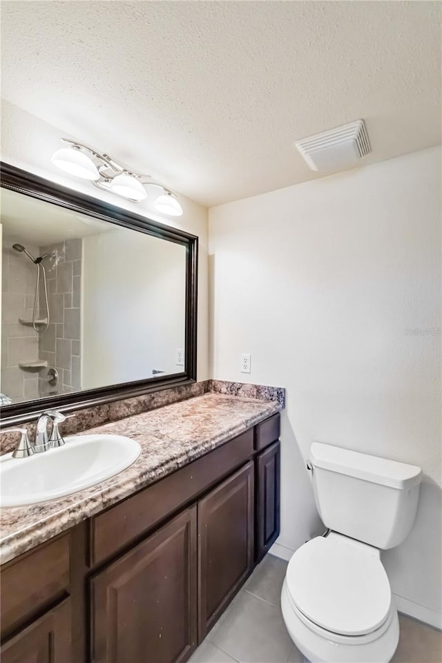 bathroom featuring vanity, tiled shower, a textured ceiling, and toilet