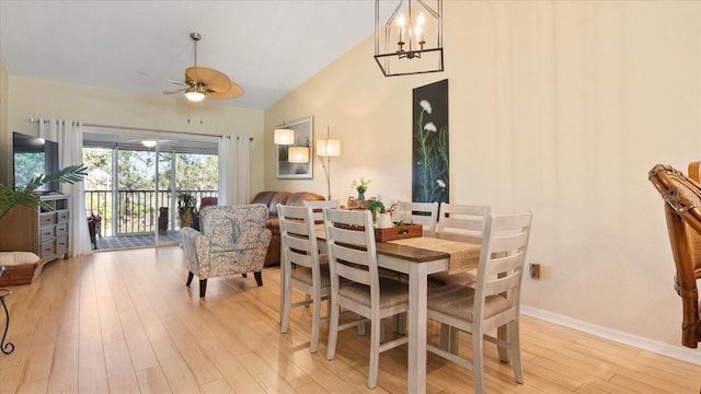 dining area featuring high vaulted ceiling, ceiling fan with notable chandelier, and light wood-type flooring