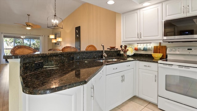 kitchen featuring white cabinetry, sink, dark stone countertops, kitchen peninsula, and white appliances