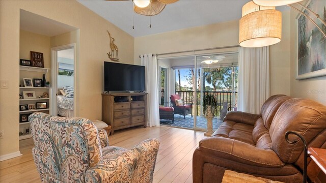 living room with ceiling fan, vaulted ceiling, and light wood-type flooring