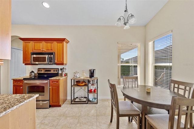 kitchen with light stone counters, decorative light fixtures, a chandelier, light tile patterned floors, and stainless steel appliances