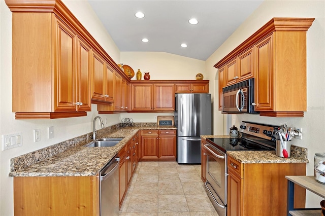 kitchen with sink, stone countertops, vaulted ceiling, light tile patterned floors, and stainless steel appliances