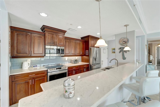 kitchen with a breakfast bar, sink, hanging light fixtures, stainless steel appliances, and backsplash