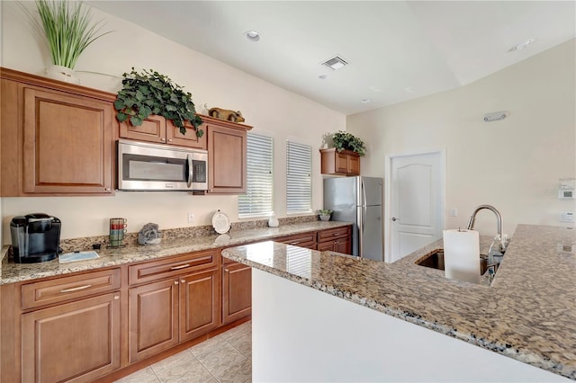 kitchen with light stone counters, stainless steel appliances, and sink