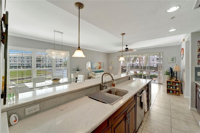 kitchen featuring ornamental molding, sink, light stone counters, and decorative light fixtures