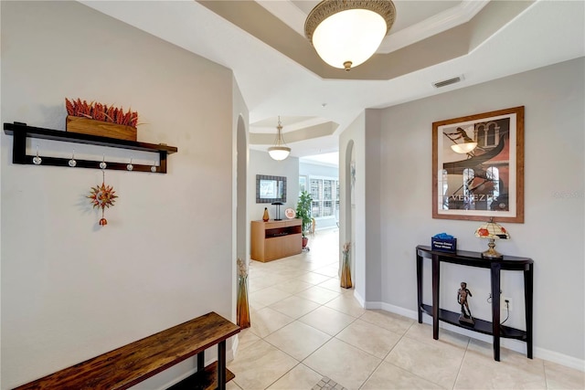 hallway featuring a raised ceiling and light tile patterned floors