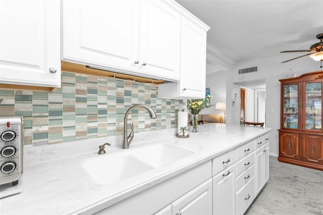 kitchen featuring ceiling fan, sink, decorative backsplash, and white cabinets