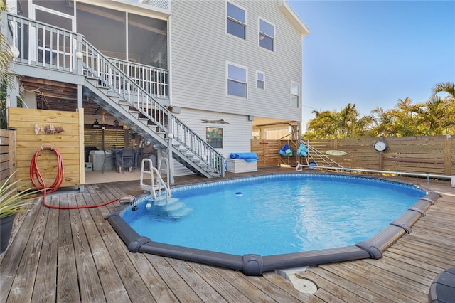 view of pool with a sunroom and a deck