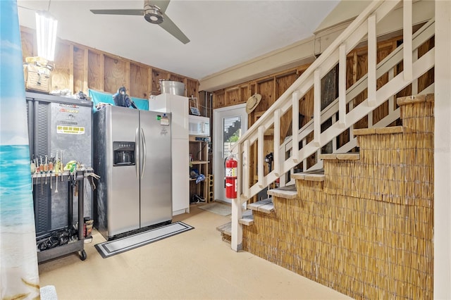 kitchen with stainless steel fridge, ceiling fan, and wood walls