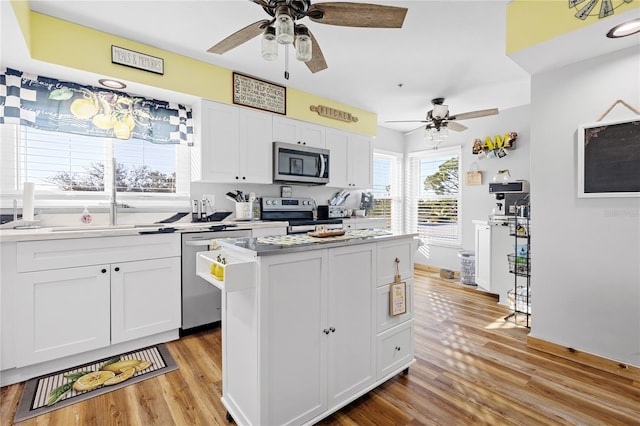 kitchen featuring white cabinetry, appliances with stainless steel finishes, a center island, and light wood-type flooring