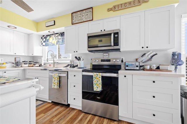 kitchen featuring stainless steel appliances, white cabinetry, and light hardwood / wood-style flooring