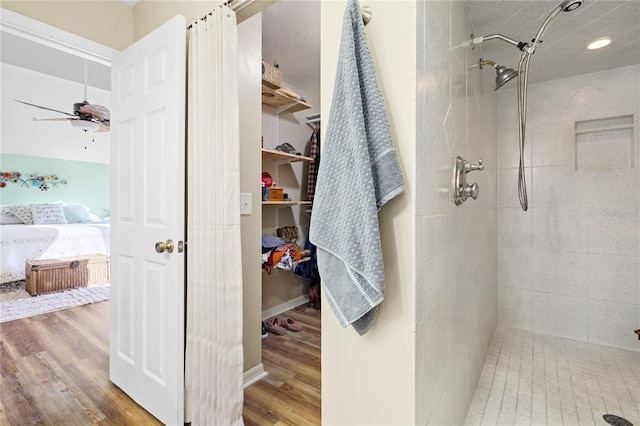 bathroom with tiled shower, hardwood / wood-style floors, and ceiling fan