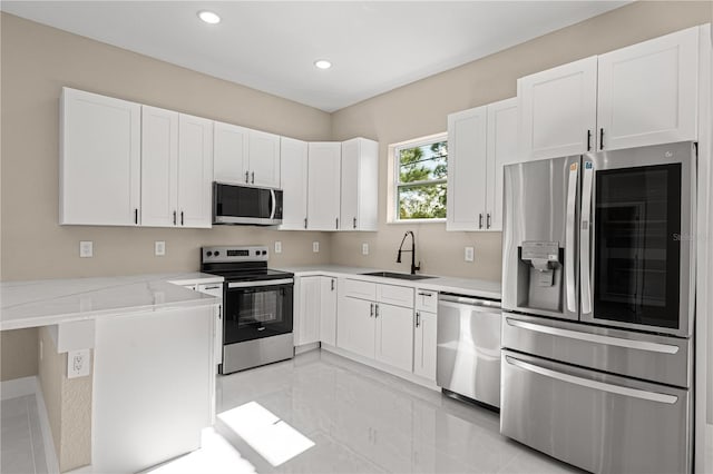 kitchen with sink, kitchen peninsula, stainless steel appliances, light stone countertops, and white cabinets