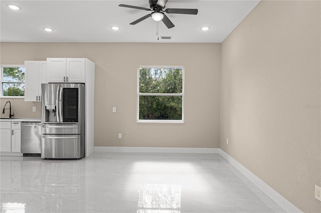 kitchen with stainless steel appliances, sink, white cabinets, and ceiling fan