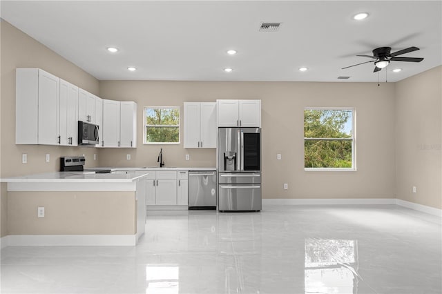 kitchen featuring stainless steel appliances, sink, a wealth of natural light, and white cabinets